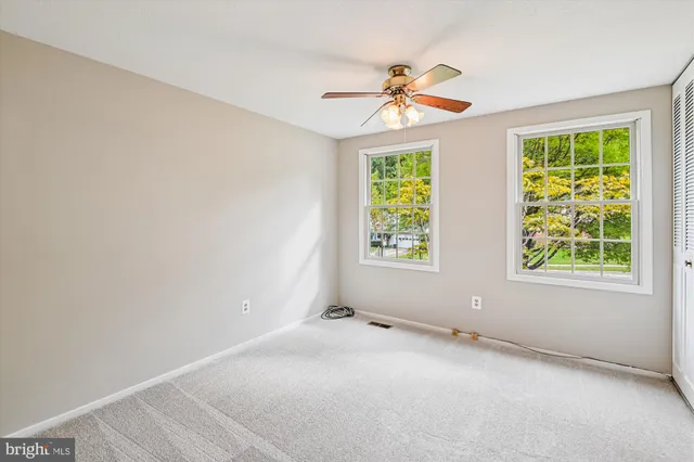 an empty room with windows and fan