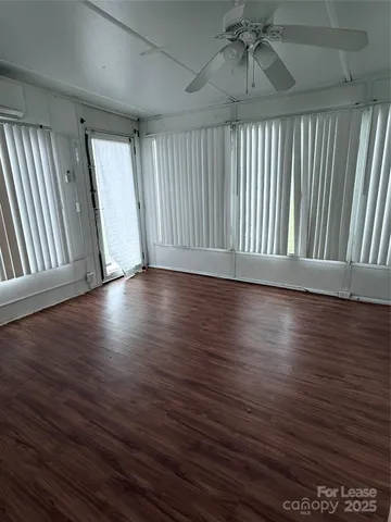 an empty room with wooden floor fan and windows