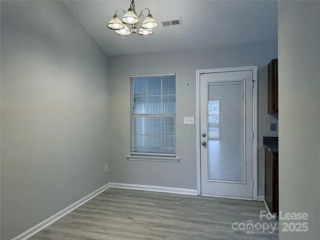 an empty room with wooden floor closet and windows