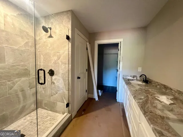 a bathroom with a granite countertop sink a mirror and shower