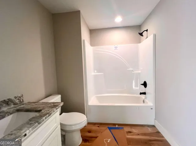 a bathroom with a granite countertop toilet and a bathtub