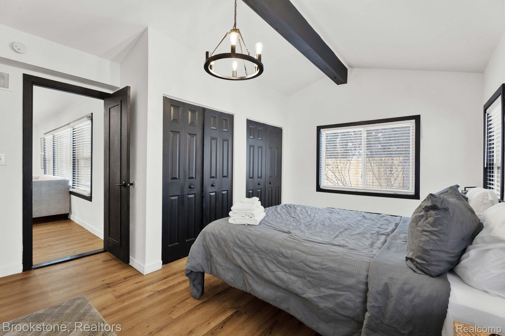 16046 West 13 Mile Road Franklin, MI 48025 - Photo 19 of 31 Bedroom featuring two closets, light wood-style floors, beamed ceiling, and hanging lights