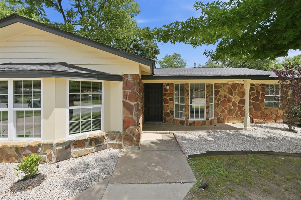 1108 Billie Ruth Lane Hurst, TX 76053 - Photo 2 of 27 Exterior featuring a stone facade, beige siding, bay window with grid-patterned panes, covered entry, and gravel landscaping