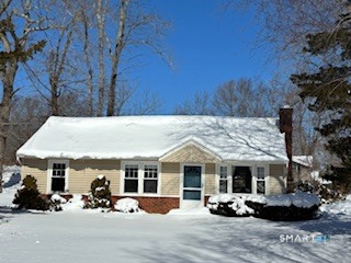 a view of a white house with large trees and outdoor seating