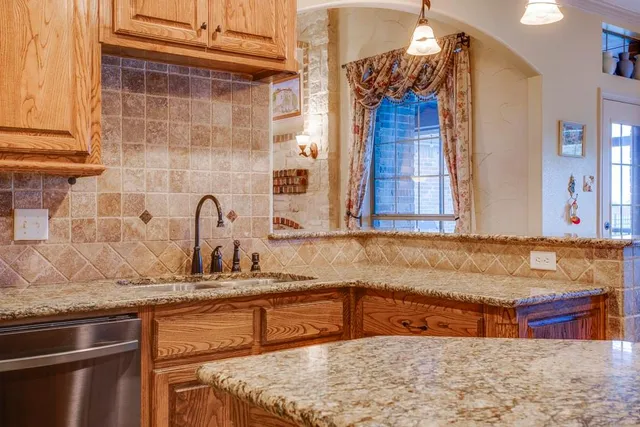 a kitchen with stainless steel appliances granite countertop a sink a stove and a wooden cabinets