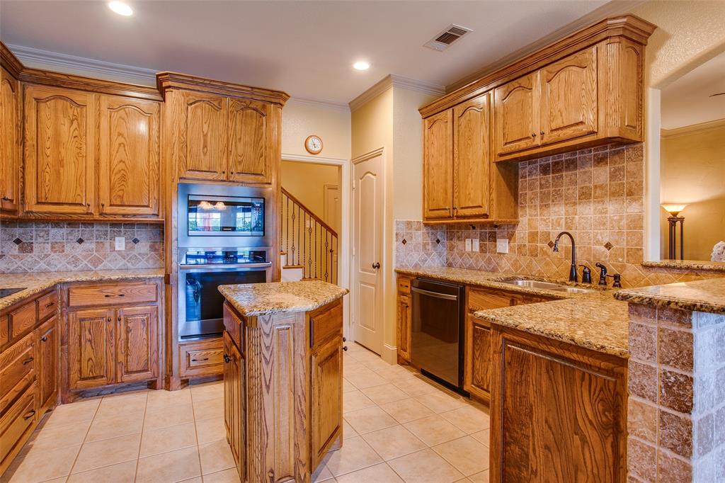 10044 Dennehy Drive Talty, TX 75126 - Photo 17 of 40 a kitchen with stainless steel appliances granite countertop a sink stove and refrigerator