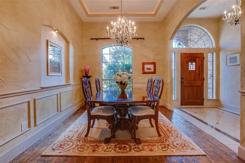 a dining room with wooden floor a chandelier a wooden table and chairs