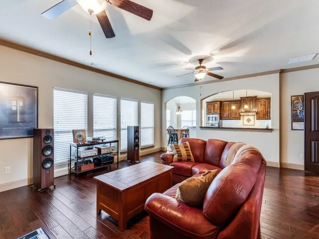 a living room with furniture a ceiling fan and a large window