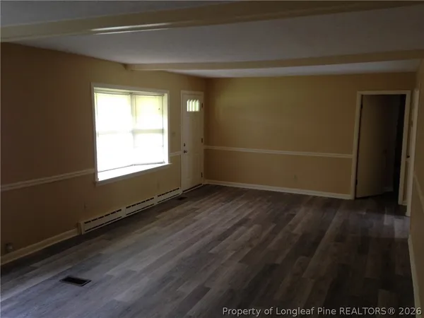a view of an empty room with wooden floor and a window