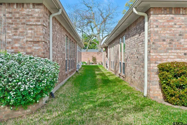 a view of a pathway of a house with a big yard plants and large trees