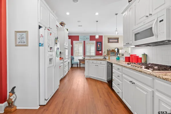 a kitchen with stainless steel appliances a sink dishwasher stove refrigerator and cabinets with wooden floor