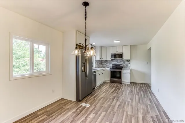 a kitchen with refrigerator a stove and white cabinets