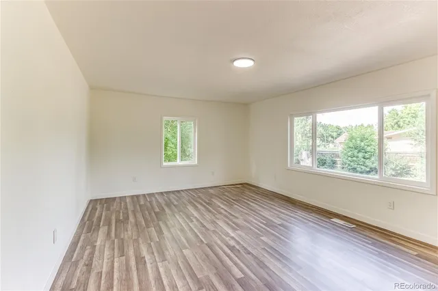 an empty room with wooden floor and windows