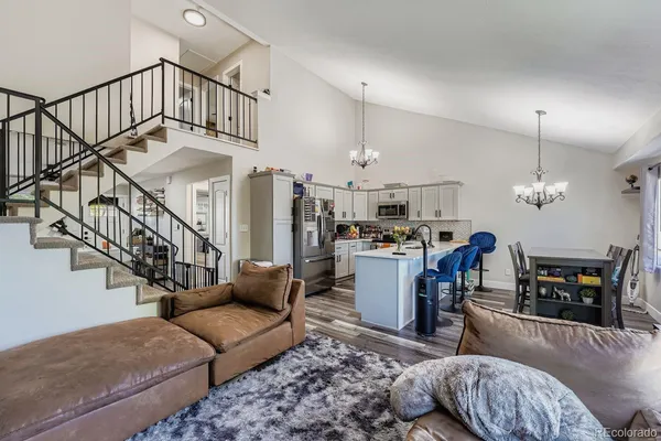 a living room with furniture kitchen view and a chandelier