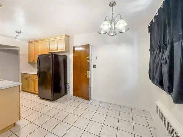 a view of a refrigerator in kitchen and an empty room