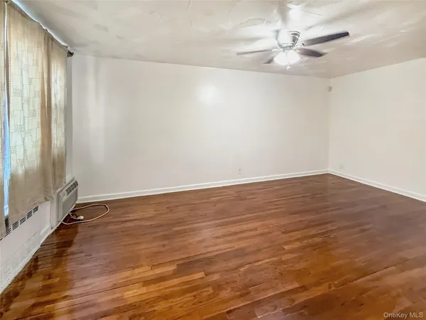 an empty room with wooden floor and fan