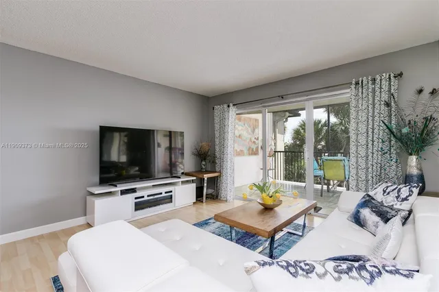 a living room with furniture a flat screen tv and a floor to ceiling window