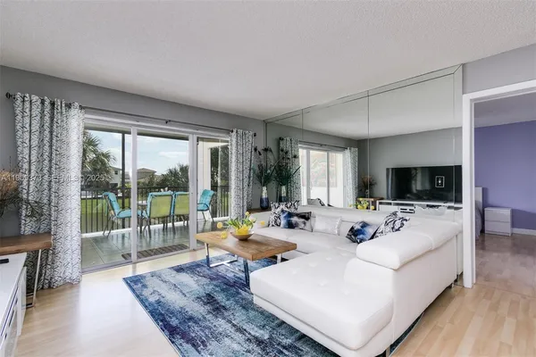 a living room with furniture a flat screen tv and a large window