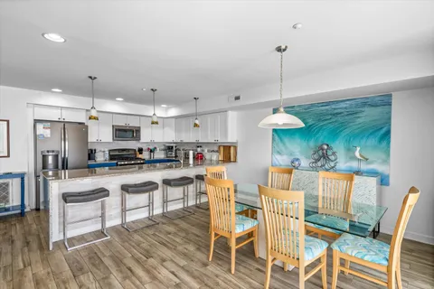 a kitchen with stainless steel appliances granite countertop a stove a refrigerator a kitchen island a sink and chairs