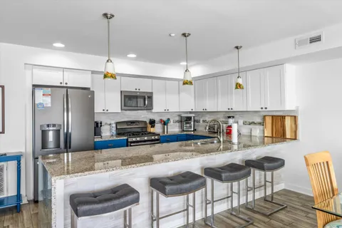 a living room with stainless steel appliances granite countertop furniture wooden floor and a kitchen view
