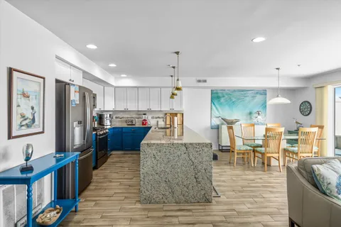 a living room with stainless steel appliances furniture wooden floor and a kitchen view