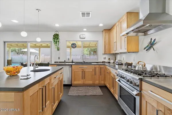 a kitchen with a refrigerator a sink dishwasher a dining table and chairs with wooden floor