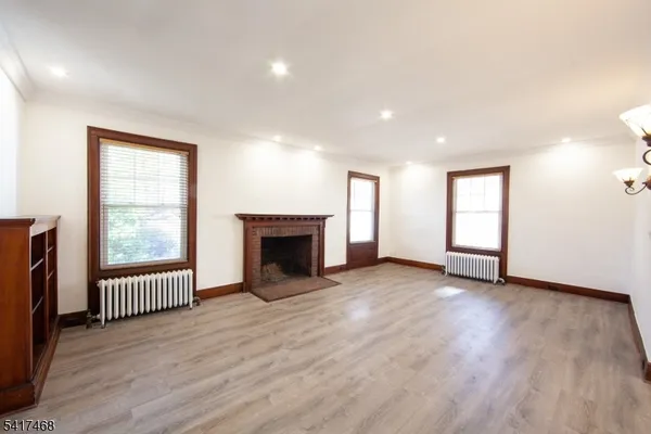 an empty room with wooden floor a fireplace and windows