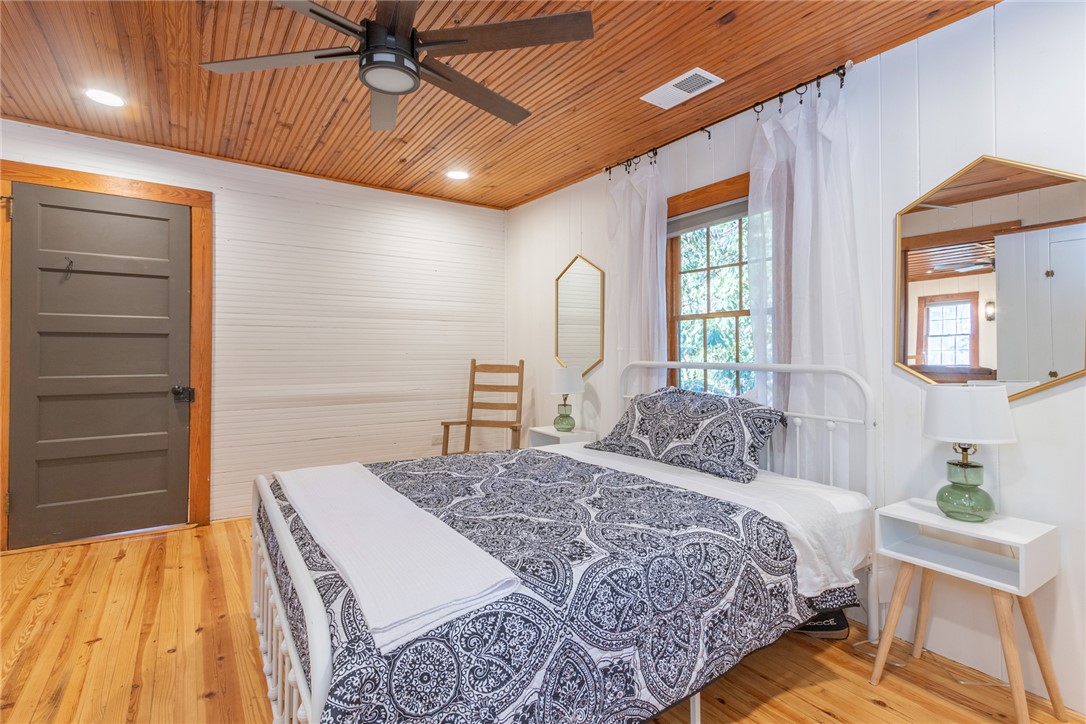 205 Rocky Bottom Road Sunset, SC 29685 - Photo 21 of 46 Rich wood plank floors and a matching tongue-and-groove ceiling frame this rustic bedroom space.