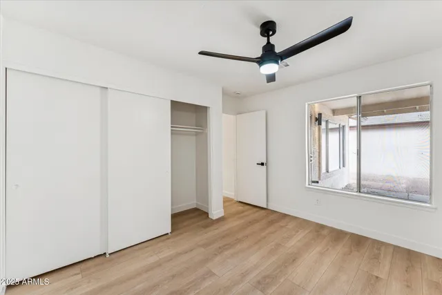 an empty room with wooden floor fan and windows