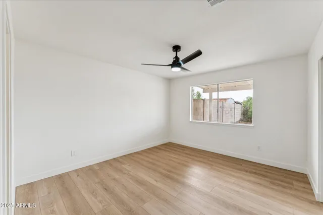 a view of empty room with wooden floor and fan