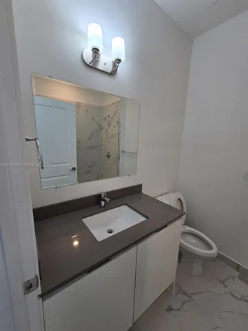 a bathroom with a granite countertop sink a toilet and mirror