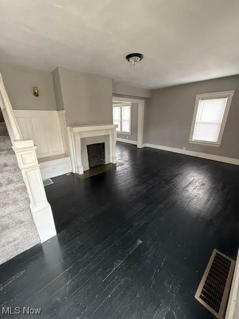 4372 Turney Road Cleveland, OH 44105 - Photo 9 of 16 Unfurnished living room featuring dark wood-style flooring, a fireplace, and stairs