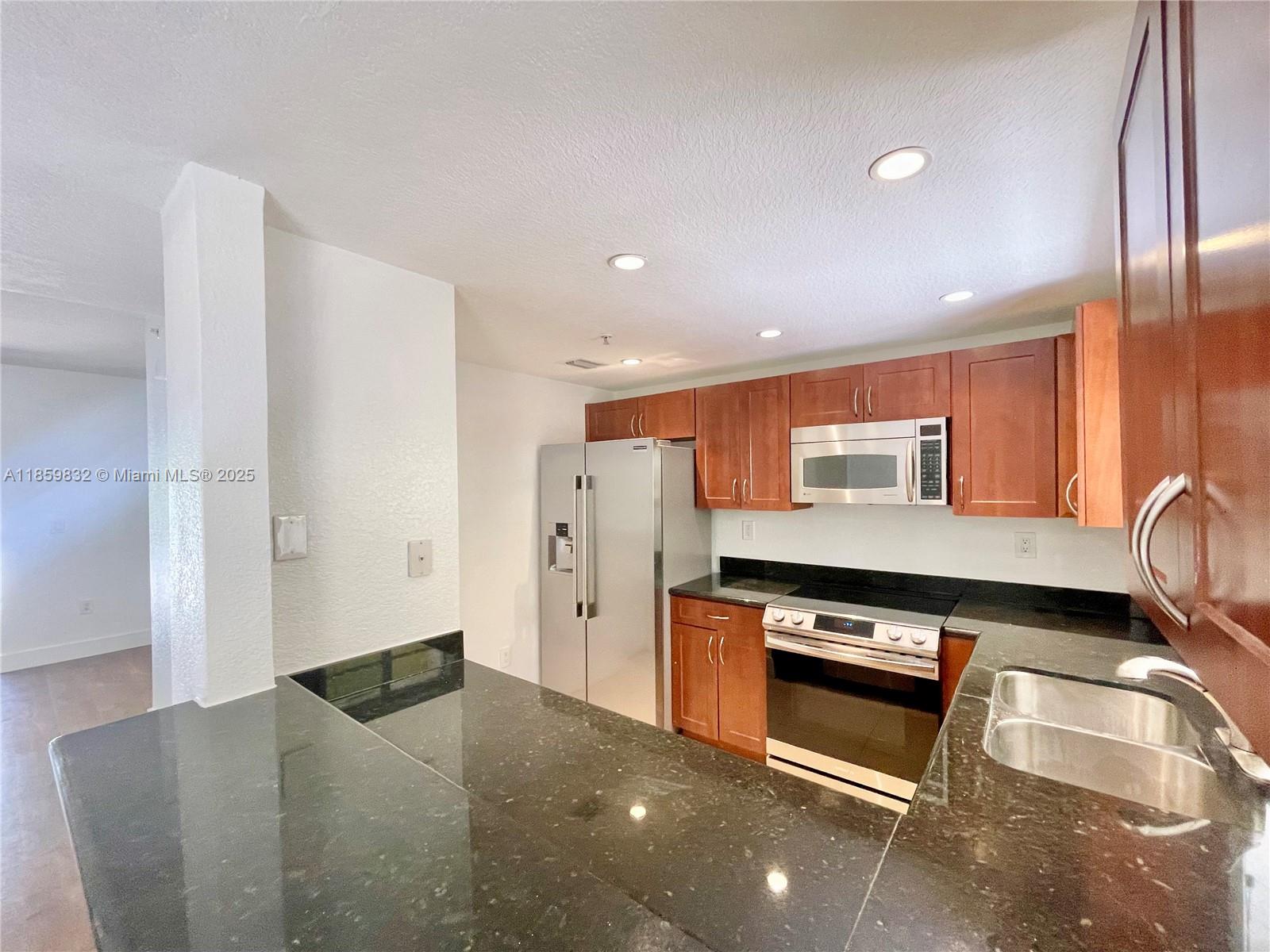 3204 Bird Avenue, Unit 105 Miami, FL 33133 - Photo 33 of 64 a kitchen with stainless steel appliances granite countertop a refrigerator and a stove top oven
