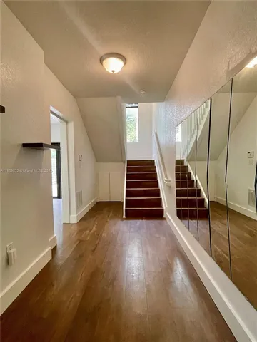 an empty room with wooden floor ceiling fan and windows