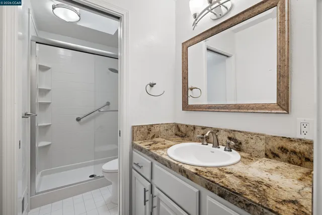 a bathroom with a granite countertop sink vanity mirror and shower