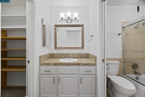 a bathroom with a granite countertop sink toilet and mirror