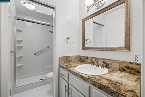 a bathroom with a granite countertop sink vanity mirror and shower