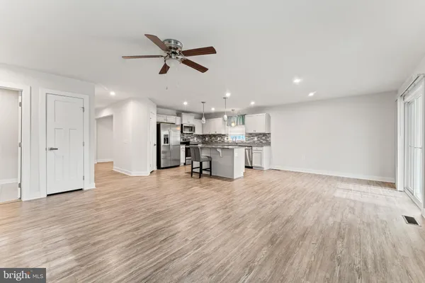 an empty room with wooden floor fan and windows