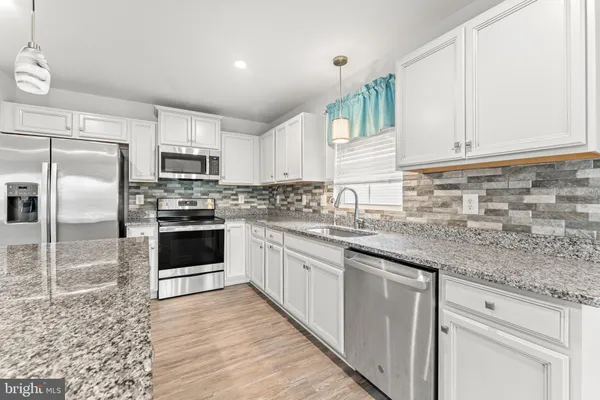a kitchen with stainless steel appliances granite countertop a stove a sink and a refrigerator