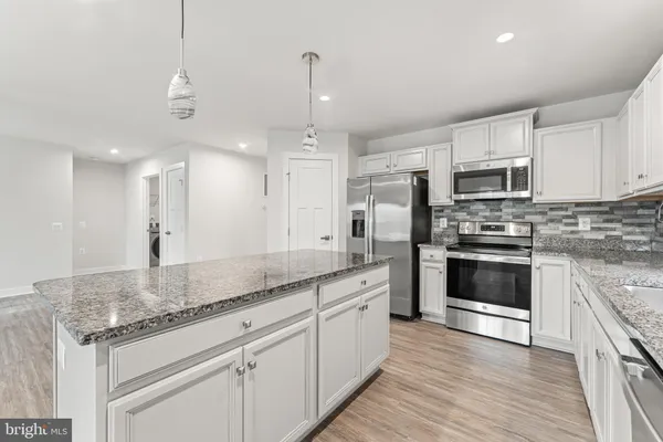 a kitchen with stainless steel appliances granite countertop a sink a stove a refrigerator a center island and cabinets