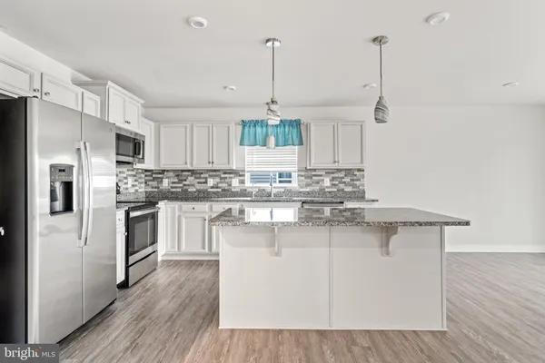 a kitchen with stainless steel appliances granite countertop a refrigerator a sink dishwasher a stove and white cabinets with wooden floor