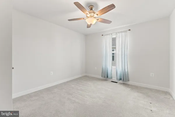 an empty room with a ceiling fan and a window