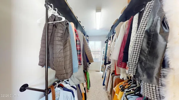 a view of walk in closet with clothes and shoes