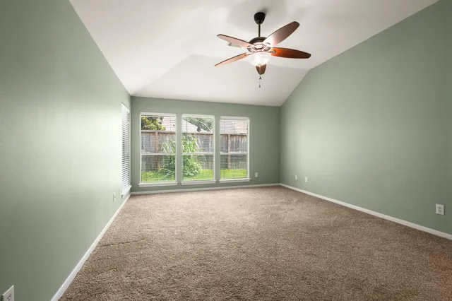 an empty room with a ceiling fan and window
