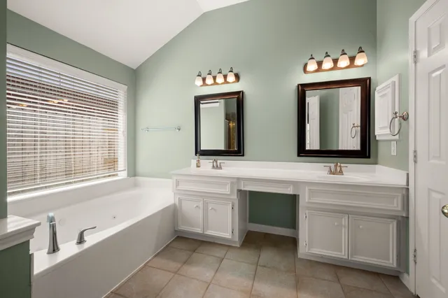 a bathroom with a tub sink and mirror