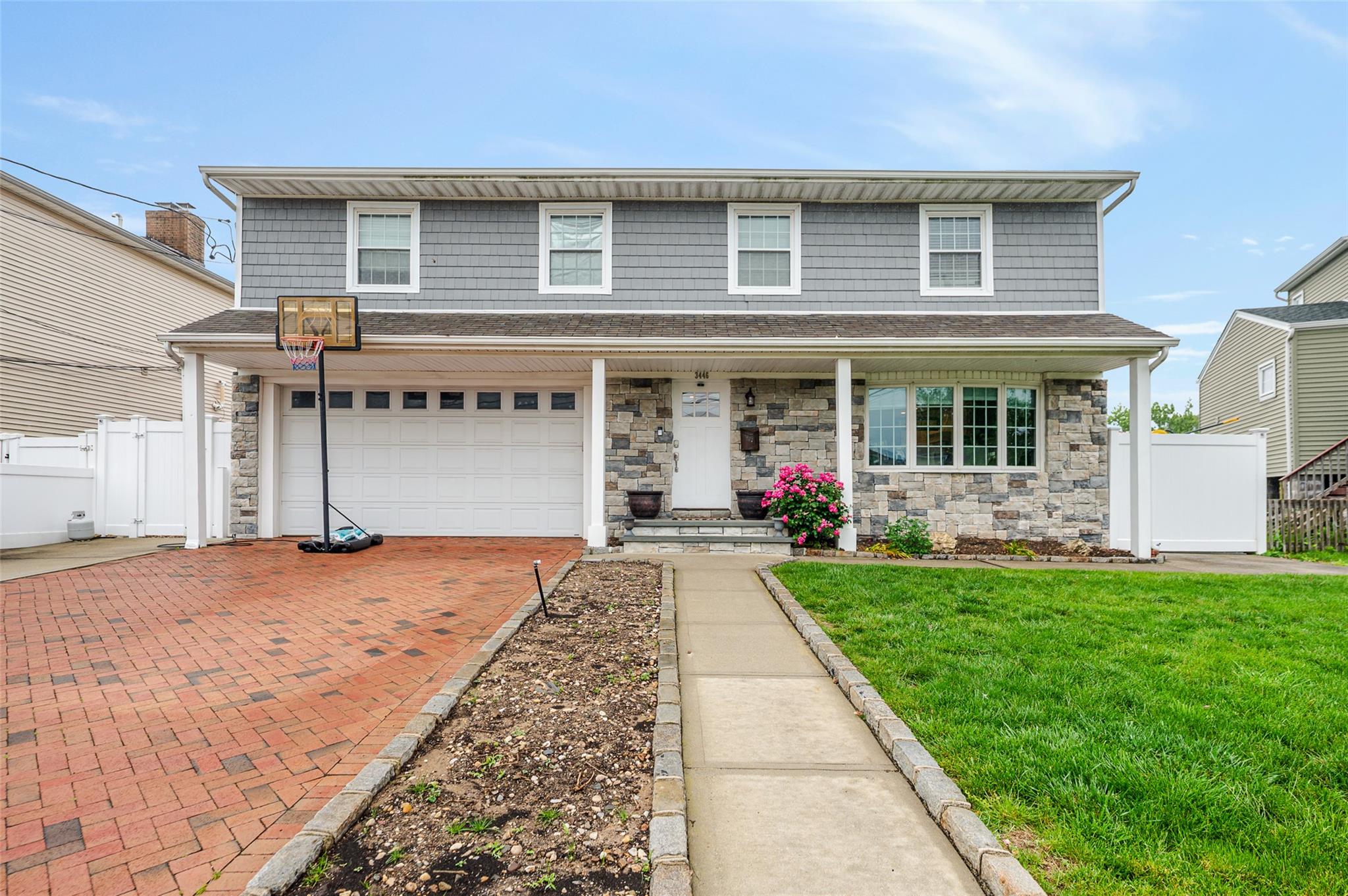 View of front of house featuring covered porch, an attached garage, decorative driveway, and stone siding