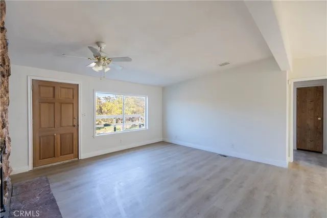 an empty room with windows chandelier fan and windows