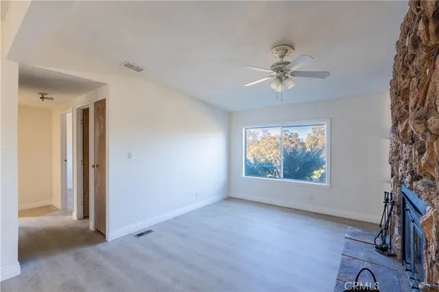 an empty room with windows and fan