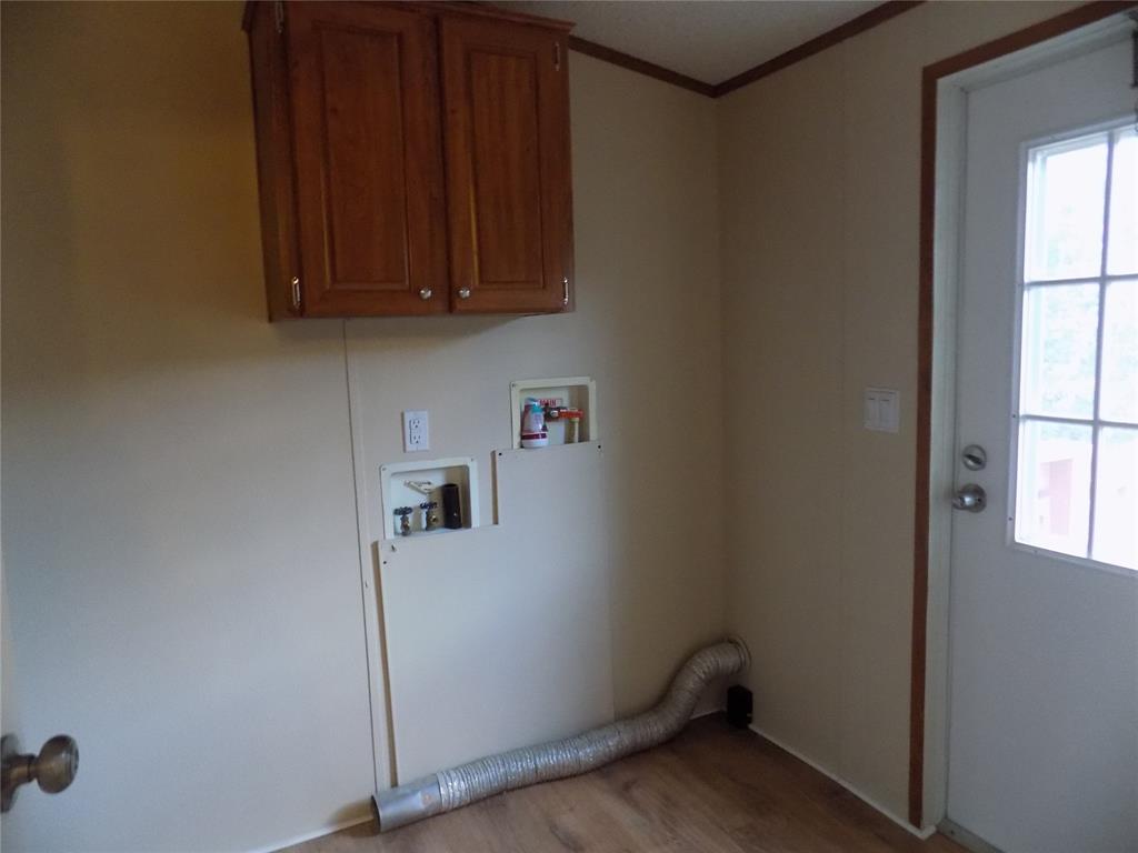 3450 Sarra Lane Springtown, TX 76082 - Photo 12 of 23 Laundry room with washer and dryer hookups, wood finished floors, and convenient cabinet space overhead.