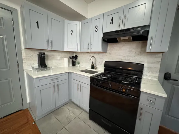 a kitchen with white cabinets a stove top oven and sink